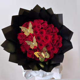 Bouquet of red roses wrapped in black paper with gold butterfly accents