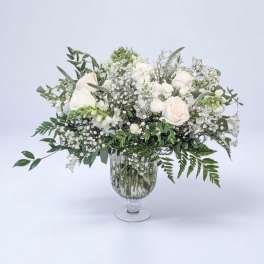 White roses and baby's breath in a clear glass vase