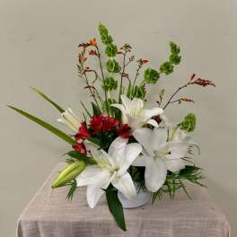 White lilies and red flowers in a white vase