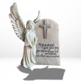 Angel figurine beside a cross memorial plaque with a Bible verse