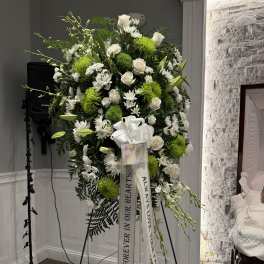 Standing sympathy spray of white and green flowers on an easel with ribbons