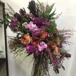 Tall floral spray with purple and peach blooms on a stand