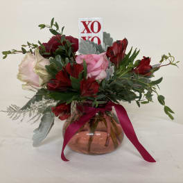 Bouquet of red and pink flowers in a glass vase with a ribbon