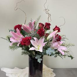 Pink lilies and red roses in a black vase
