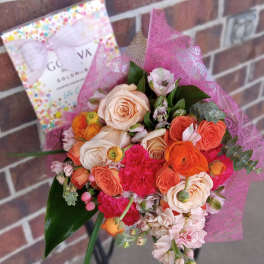 Bouquet of peach and coral roses with pink flowers and a chocolate box