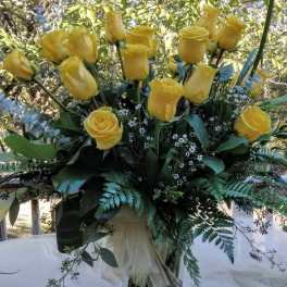 Yellow roses arranged in a clear glass vase with greenery