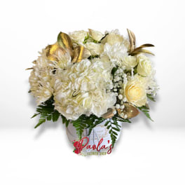 Cream bouquet with roses, hydrangeas, and gold leaves in a white container