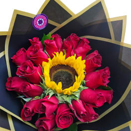 Bouquet of pink roses with a sunflower center wrapped in black paper