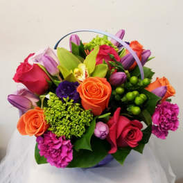 Colorful bouquet of roses, tulips, and orchids in a basket handle