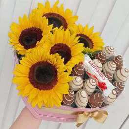 Sunflowers arranged with chocolate candies in a pink box