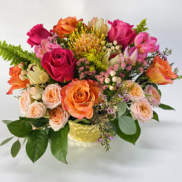Mixed bouquet of roses and tropical blooms in a yellow vase