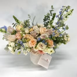 Pastel rose bouquet in a textured vase with blue accents