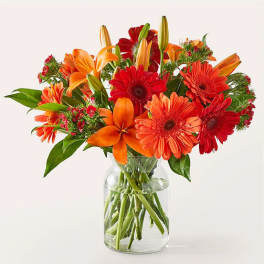 Bouquet of orange and red flowers in a clear glass vase
