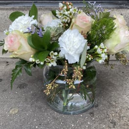 Bouquet of pale roses and white carnations in a glass vase