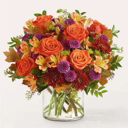 Orange roses and purple mums in a clear glass vase