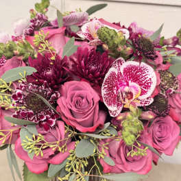 Pink roses and orchids with dark burgundy blooms in a bouquet