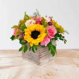 Mixed bouquet with a sunflower and pink roses in a wooden box
