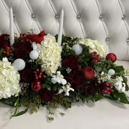 Low floral centerpiece with white hydrangeas, red roses, and candles
