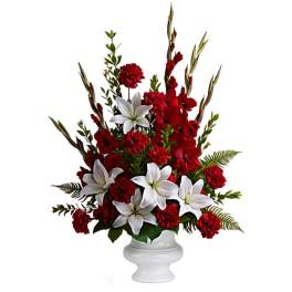 Red and white floral arrangement in a white pedestal vase