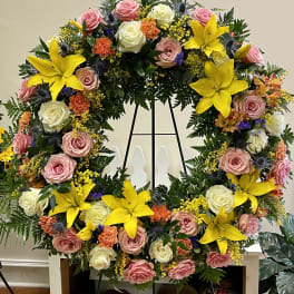 Large floral wreath with pink and white roses and bright yellow lilies