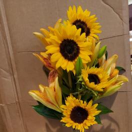 Sunflowers and lilies arranged in a tall glass vase