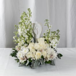 White floral arrangement with roses and a small angel figurine