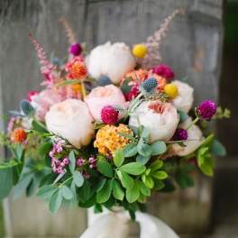 Hand-tied bouquet of pale roses and colorful accent flowers with a white ribbon
