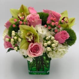 Pink roses and green orchids arranged in a green glass vase