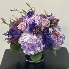Purple and pink floral arrangement in a black vase