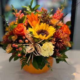 Autumn bouquet with sunflowers, orange roses, and a pumpkin vase