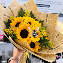 Bouquet of sunflowers wrapped in newspaper-style paper with butterfly accents.