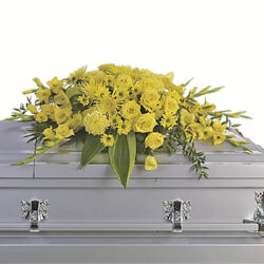 Yellow floral casket spray on a gray casket