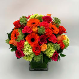 Bright mixed bouquet of roses, gerberas, carnations, and hydrangeas in a glass vase