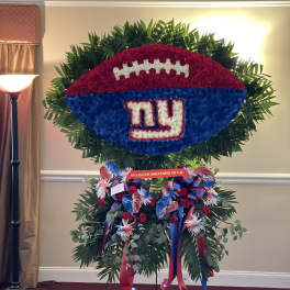 Large football-shaped floral tribute with a Giants logo and ribbon accents