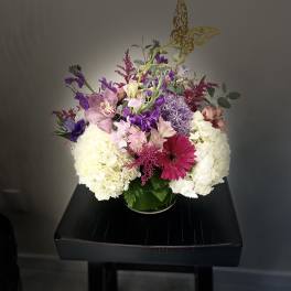 Mixed bouquet of white, pink, and purple flowers in a glass vase