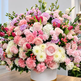 Large pink and white floral arrangement in a white vase