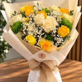 Bouquet of yellow and cream roses with white baby's breath and green button mums