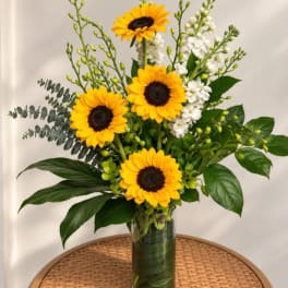 Sunflowers and white flowers arranged in a clear glass vase