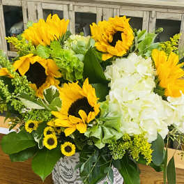 Sunflower and white hydrangea arrangement in a lace-wrapped vase