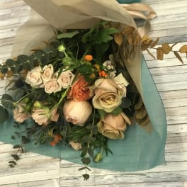 Bouquet of blush and peach roses wrapped in tan and teal paper