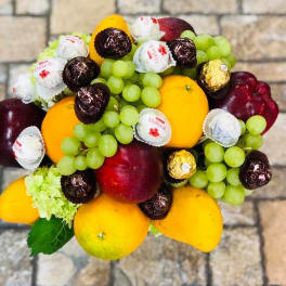 Fruit arrangement with grapes, mangoes, apples, and wrapped chocolates