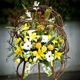 Yellow and white floral arrangement in a twig wreath stand