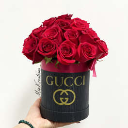 Red roses arranged in a black Gucci hat box