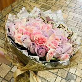 Bouquet of pastel pink and lavender roses wrapped in decorative paper