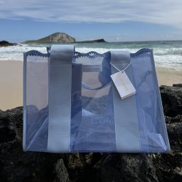 Translucent blue crochet tote with wide light-blue straps, clear body and branded hanging tag.