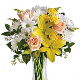 Bouquet of yellow lilies, peach roses, and white daisies in a clear glass vase
