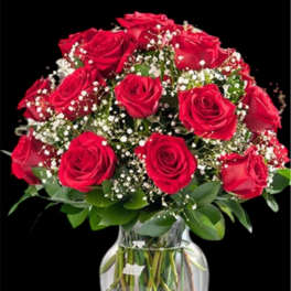 Red roses arranged in a clear glass vase with baby's breath