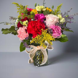 Mixed bouquet of carnations and roses in a glass vase with a ribbon