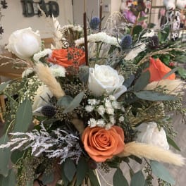 Hand-tied bouquet of orange and white roses with dried grasses