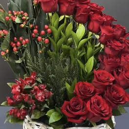 Tall arrangement of red roses with greens in a white woven basket